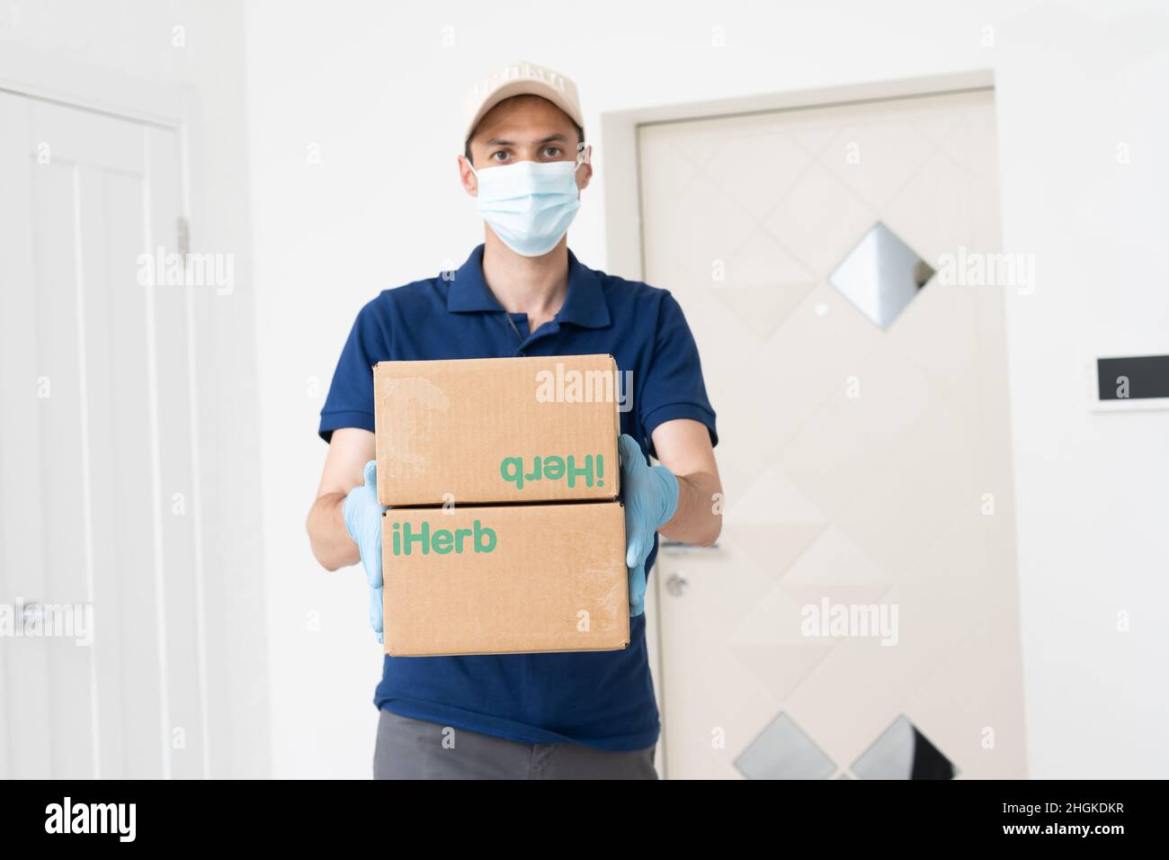 Man from delivery service in t-shirt, in protective mask and gloves ...