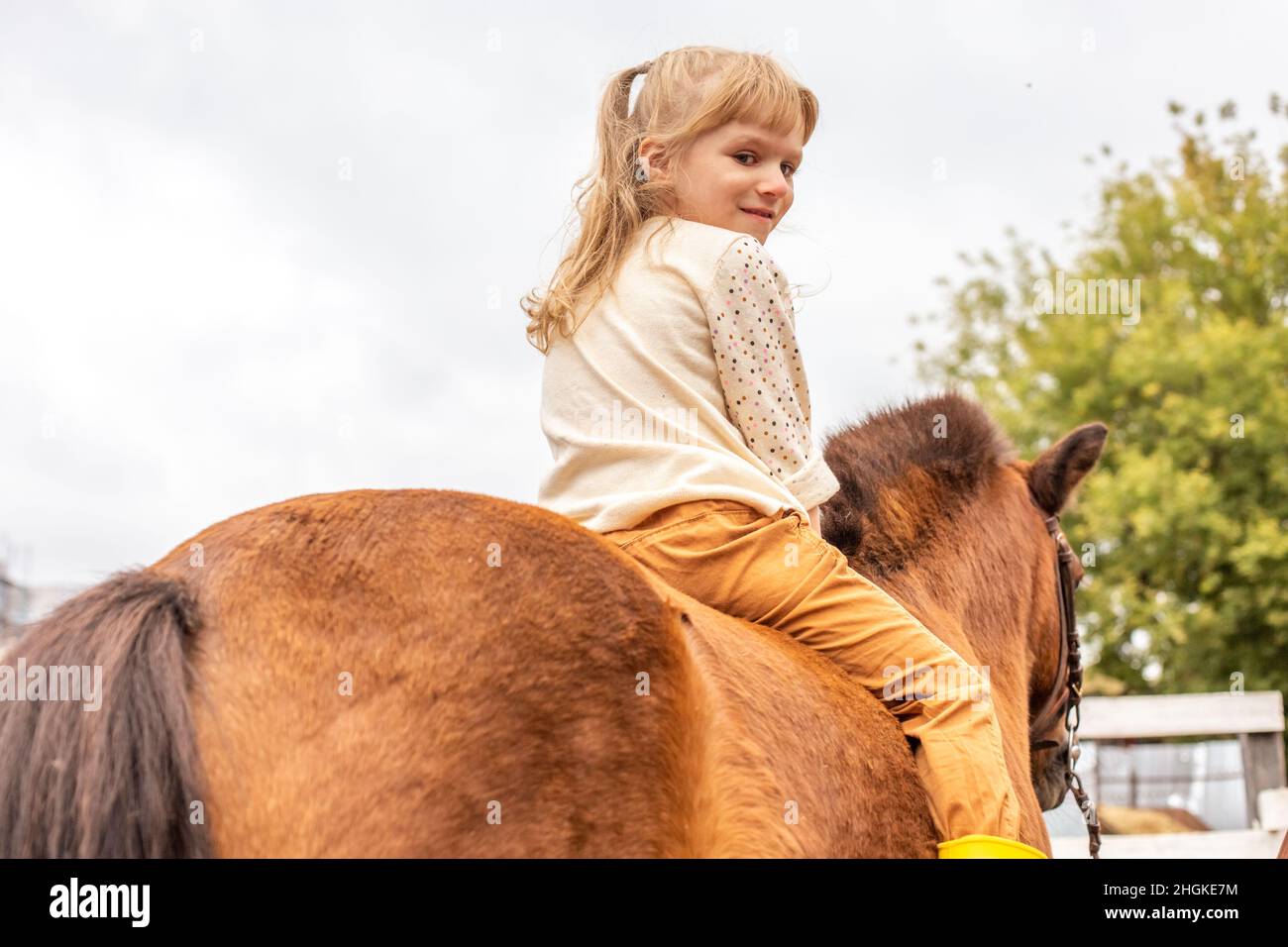 Little girl riding pony without saddle, rear view Stock Photo