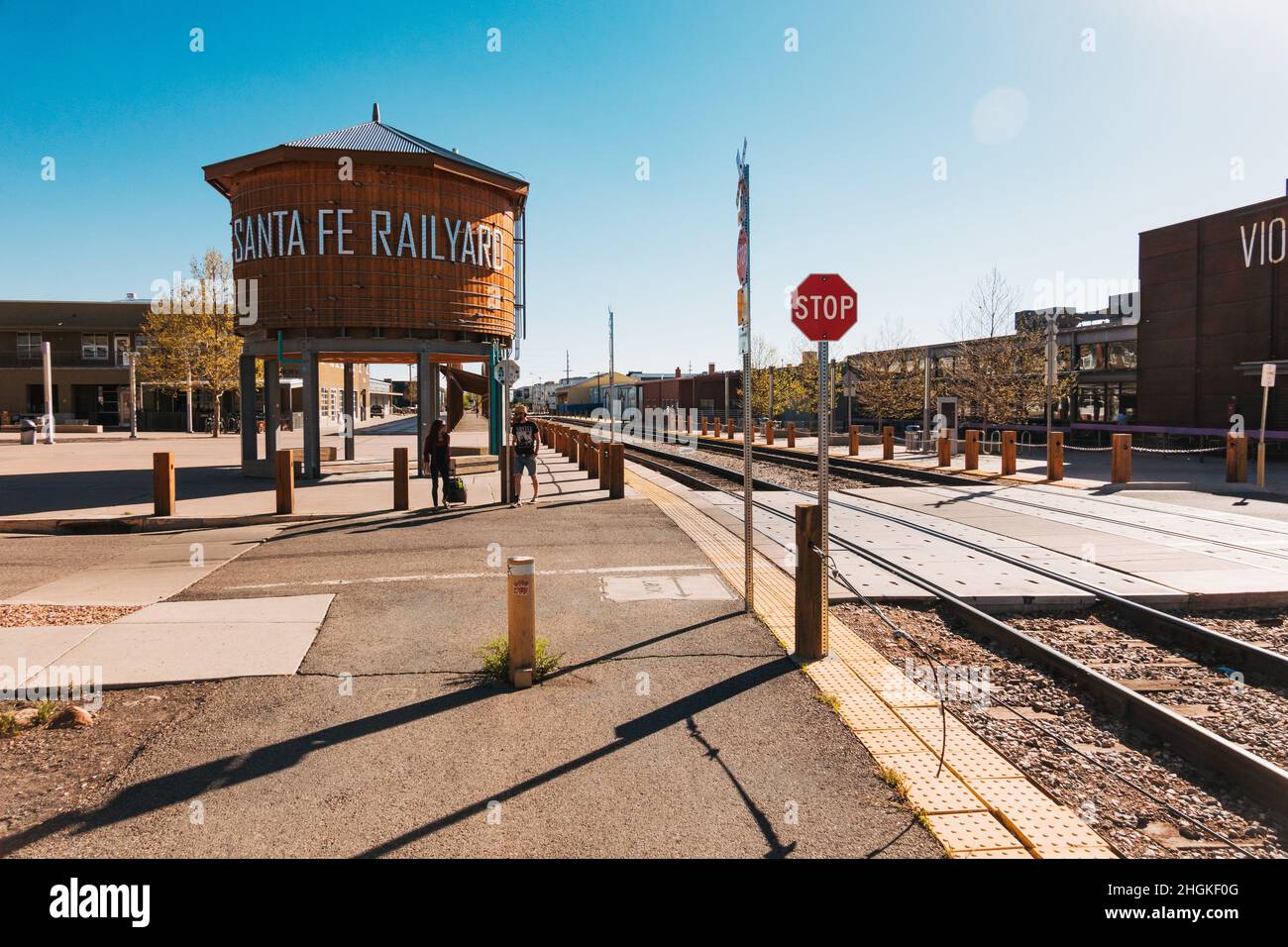 a wooden water tank with the words 'Santa Fe Railyard' next to a railroad crossing in Santa Fe, New Mexico Stock Photo
