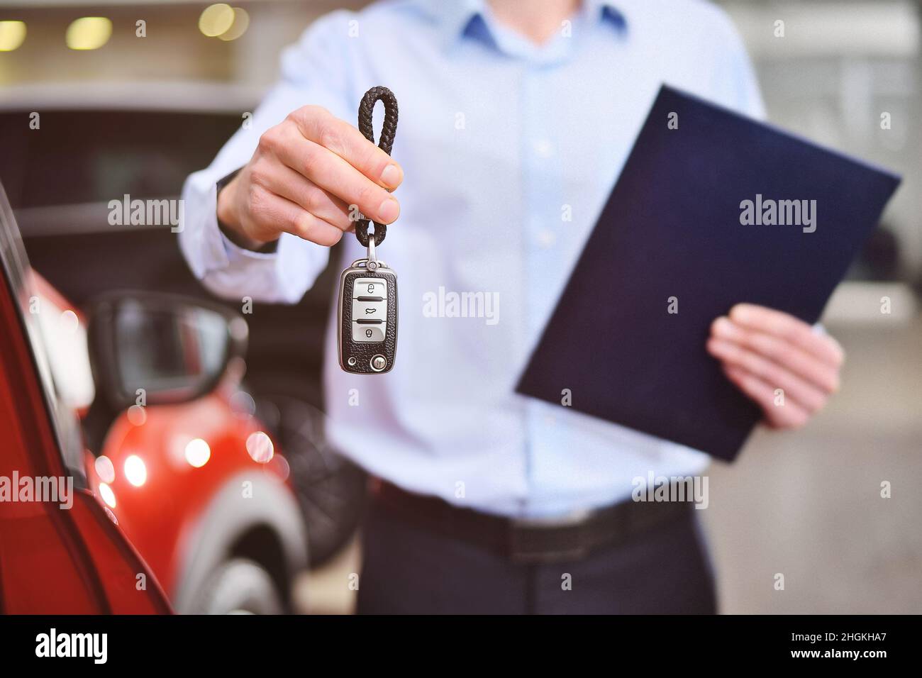 consultant or manager of a car dealership and car showroom holds car