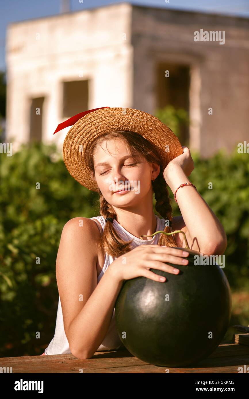 Portrait of young happy girl with hat and big whole green watermelon enjoying a outdoors. Teenager enjoying summer life. Summer lifestyle concept. Hap Stock Photo