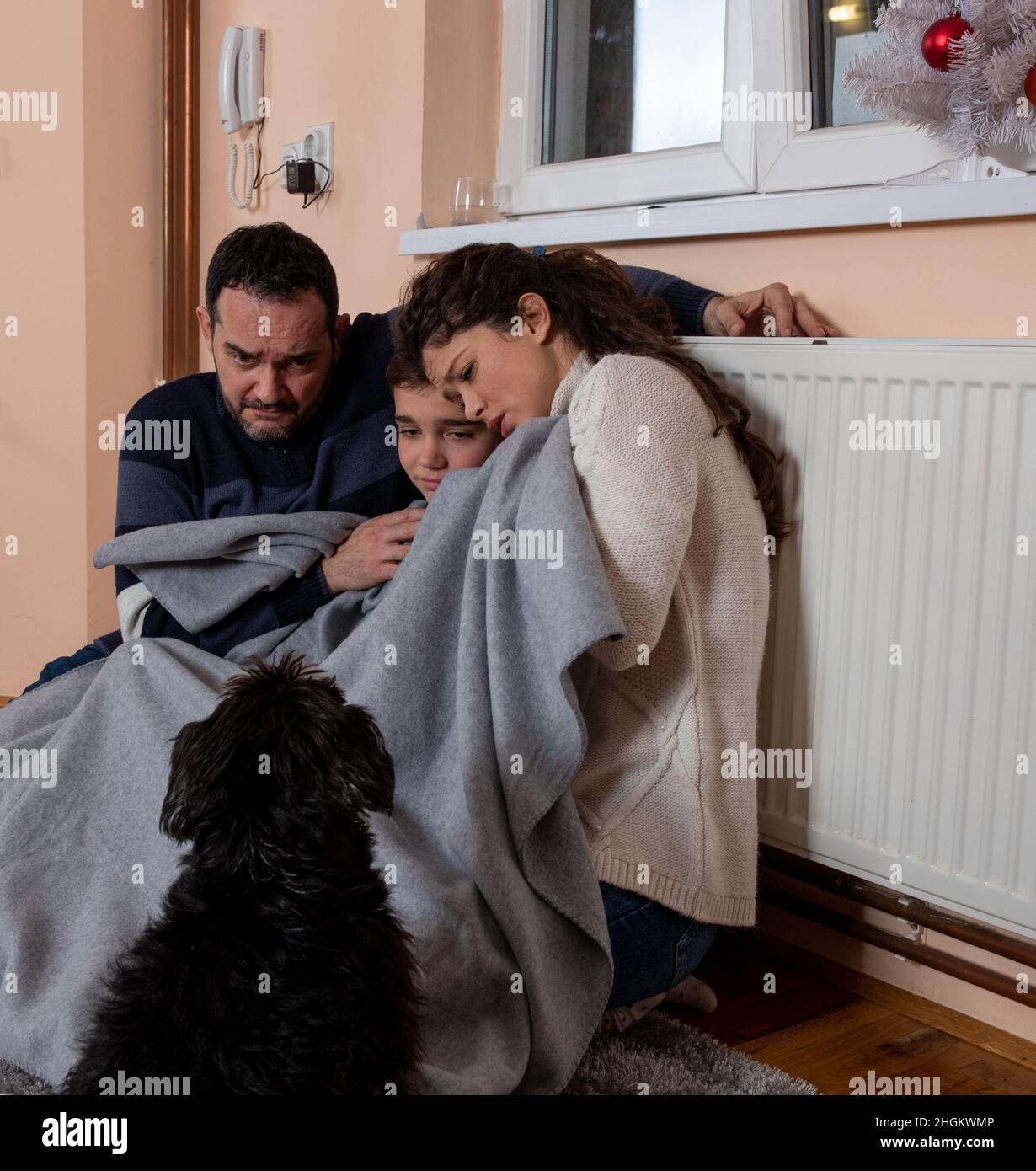 Family sits tucked under the blanket in living room suffering from cold