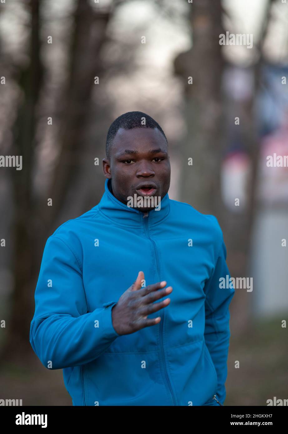 Black muscular man running in woods in winter time. Jogging and exercising on cold weather Stock Photo