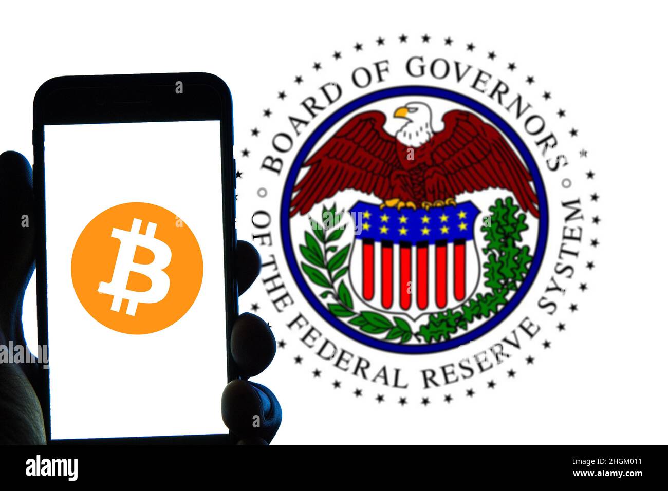 In this photo illustration a Bitcoin logo seen displayed on a smartphone  with a Board of Governors of the Federal Reserve System logo in the  background Stock Photo - Alamy