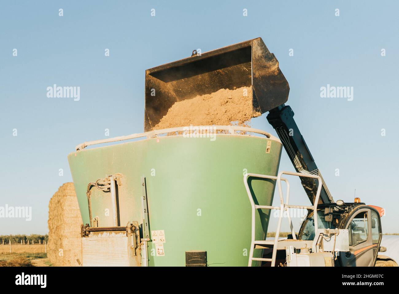 A tractor tipping animal feed inside container Stock Photo Alamy