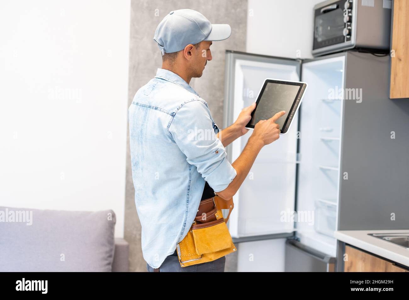 Male worker types on a tablet, kitchen renovation Stock Photo