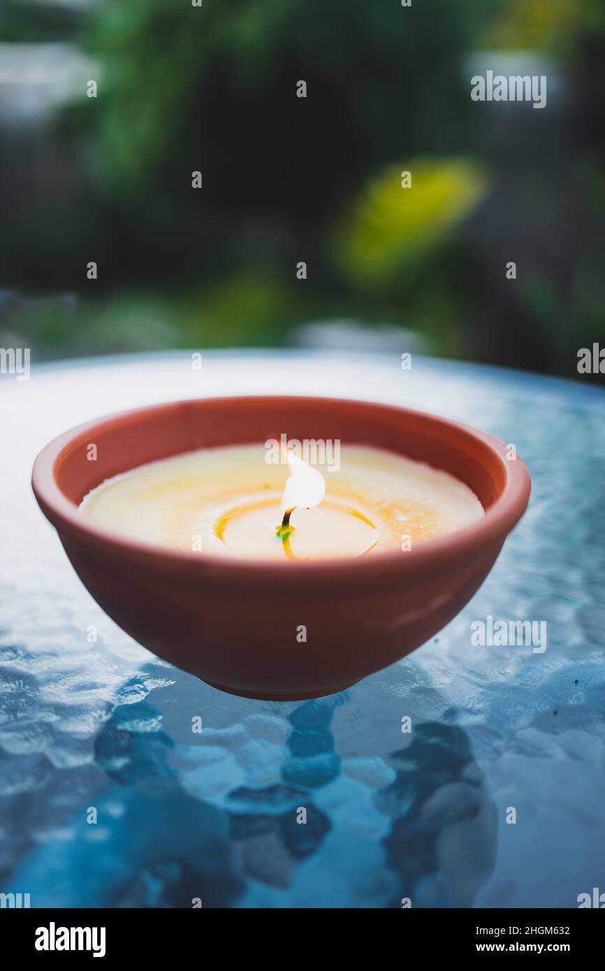 citronella candle with flame outdoor on cafe table setting at dusk for