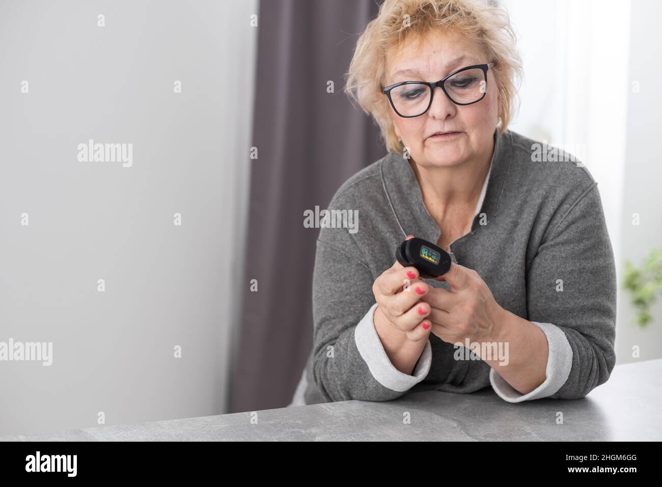 Hand of senior woman with an attached pulse oximeter on fingertip,old ...