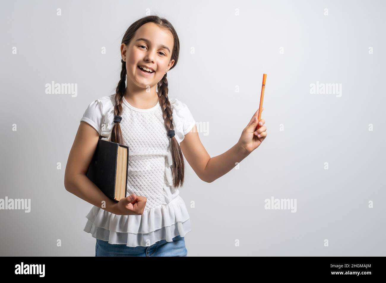 Lovely little girl standing and holding book over white background ...