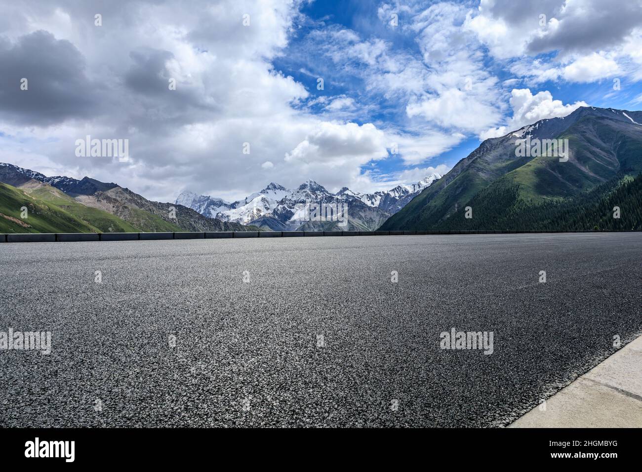 Asphalt road and snow mountain under blue sky. Highway and mountain background. Stock Photo