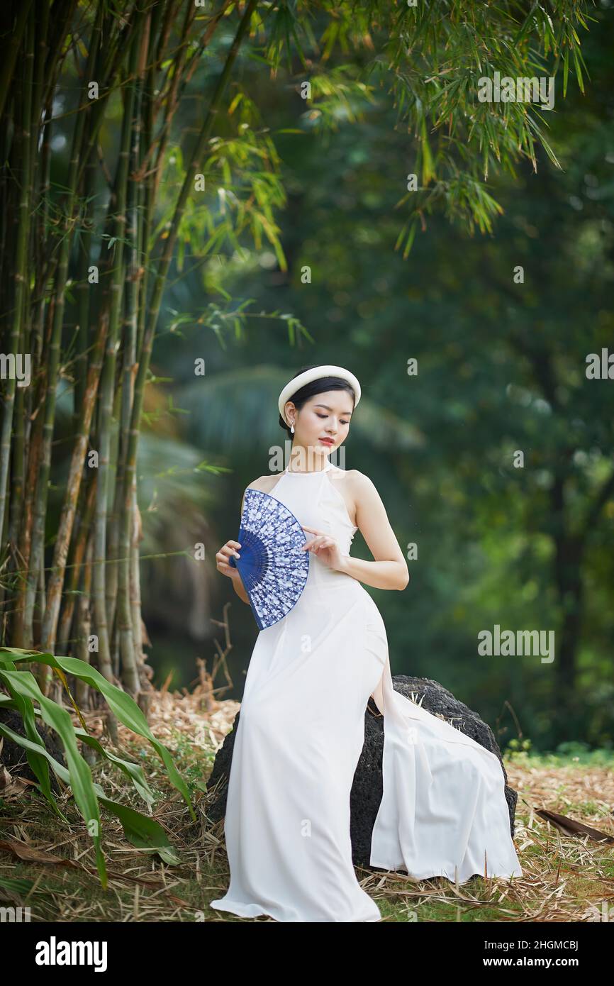 Ho Chi Minh city, Viet Nam: Ao Dai is traditional dress of vietnam,  beautiful vietnamese woman in white Ao Dai dress in the park Stock Photo -  Alamy
