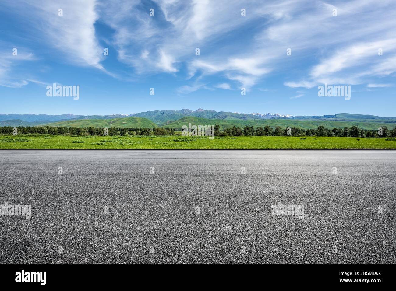 Asphalt road and green mountains under blue sky Stock Photo - Alamy
