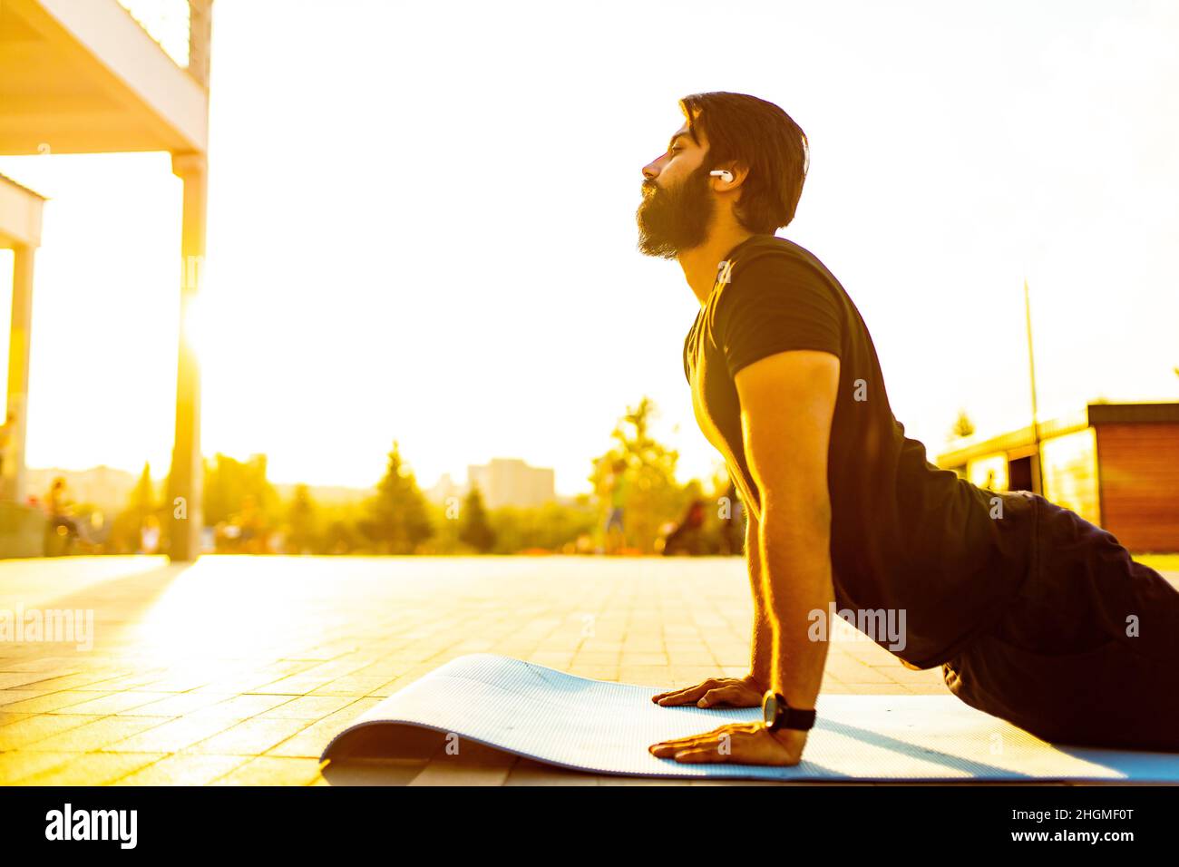 hispanic man in black cotton t-shirt ready to yoga at sunset in summer park outdoor golden lights Stock Photo