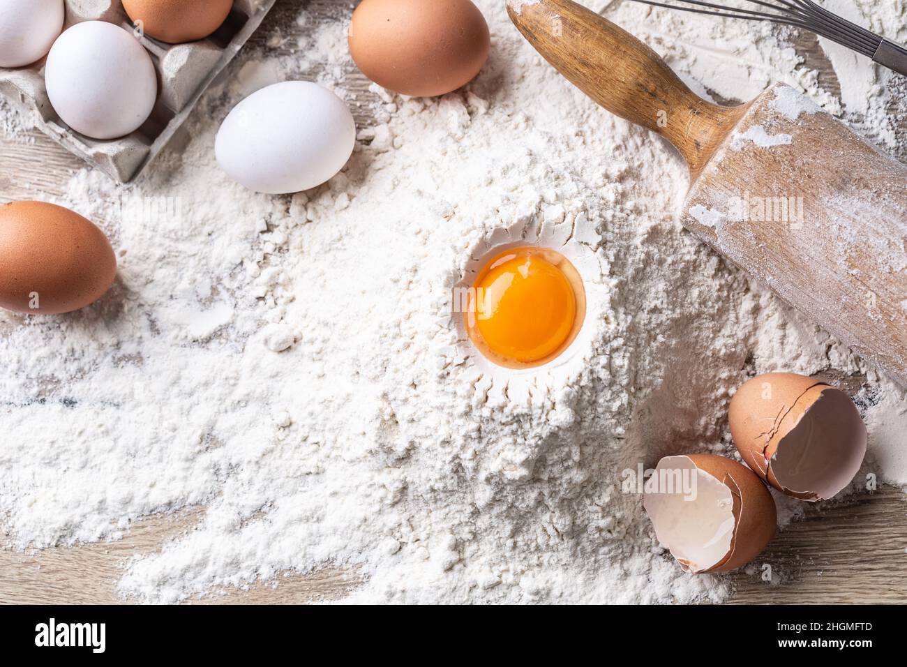 Top view of egg yolk, flour, and roller on kitchen table. Stock Photo