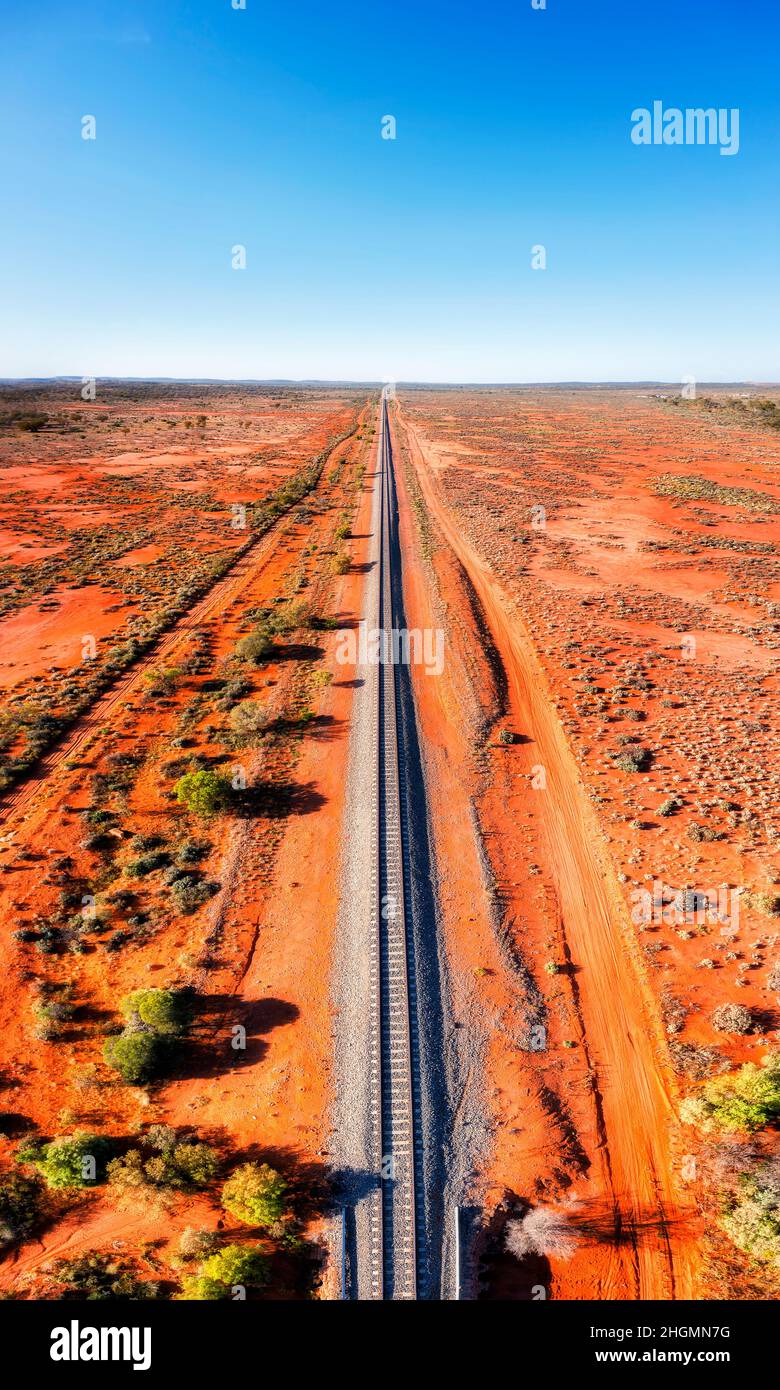 Railway track in red soil australian outback leading to Broken hill silver city of far west - aerial panorama. Stock Photo