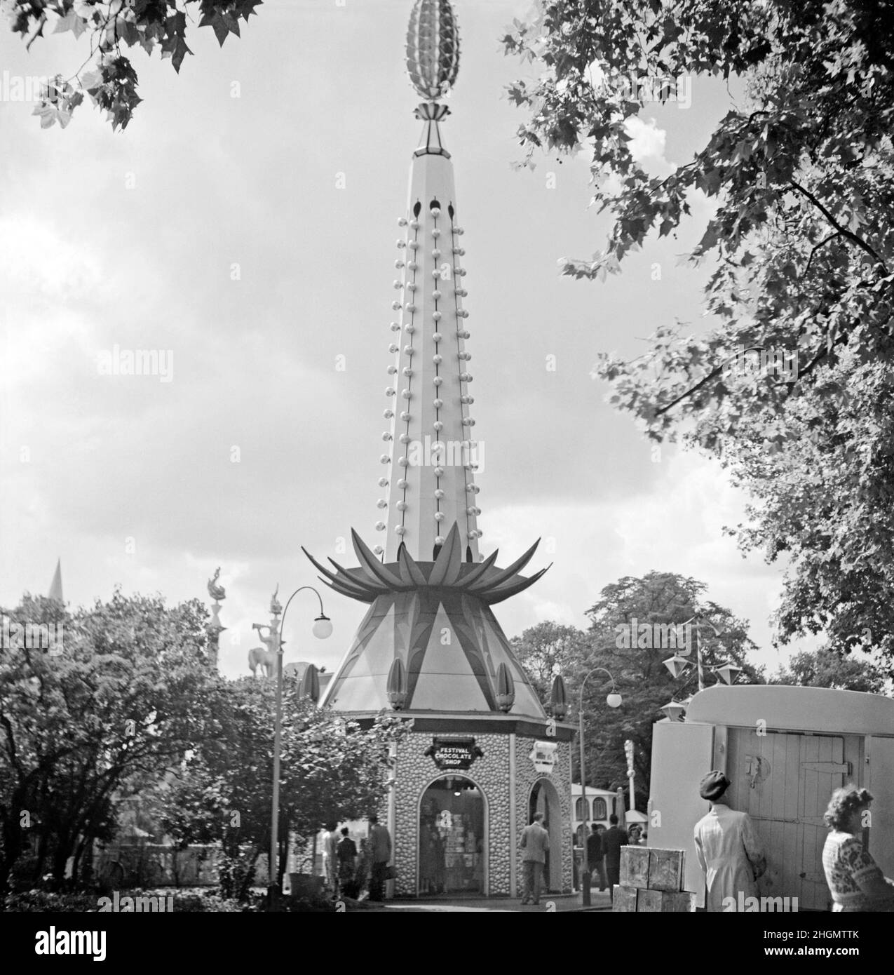 The popular ‘Festival Chocolate Shop’ at the Festival of Britain Pleasure Gardens, Battersea Park, London, England, UK during the celebrations in 1951. The pleasure gardens were an important part of the festival. A very decorative, fun design is a feature of the shop with organic ‘plant’ motifs used – a ‘pineapple’ tops off the building. It is also covered in light bulbs for night-time illumination. This image is from an old amateur black and white negative – a vintage 1950s photograph. Stock Photo