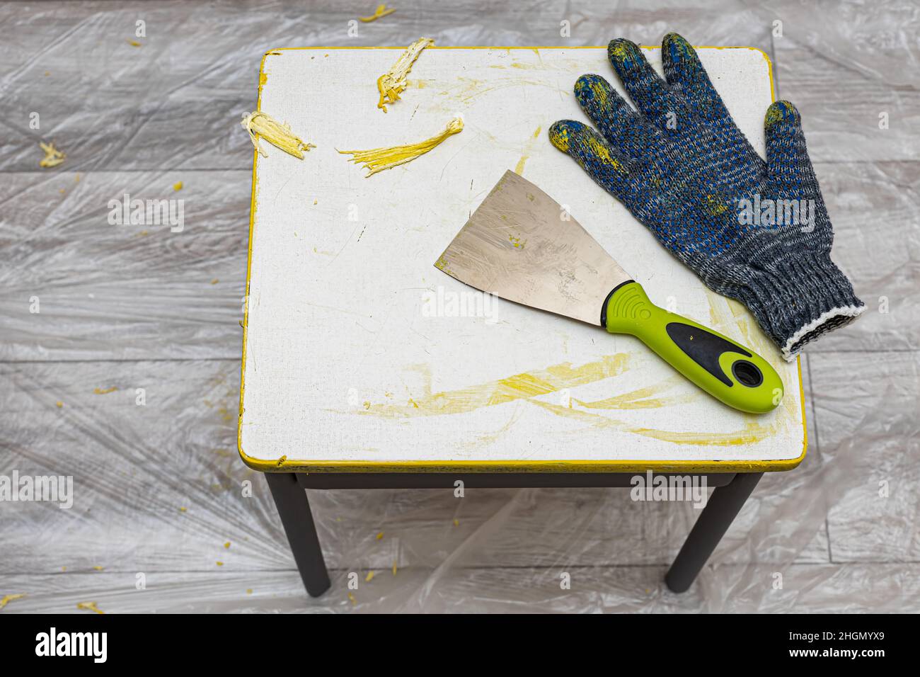 a scraper for removing paint, along with a work glove, lies on a stool. High quality photo Stock Photo