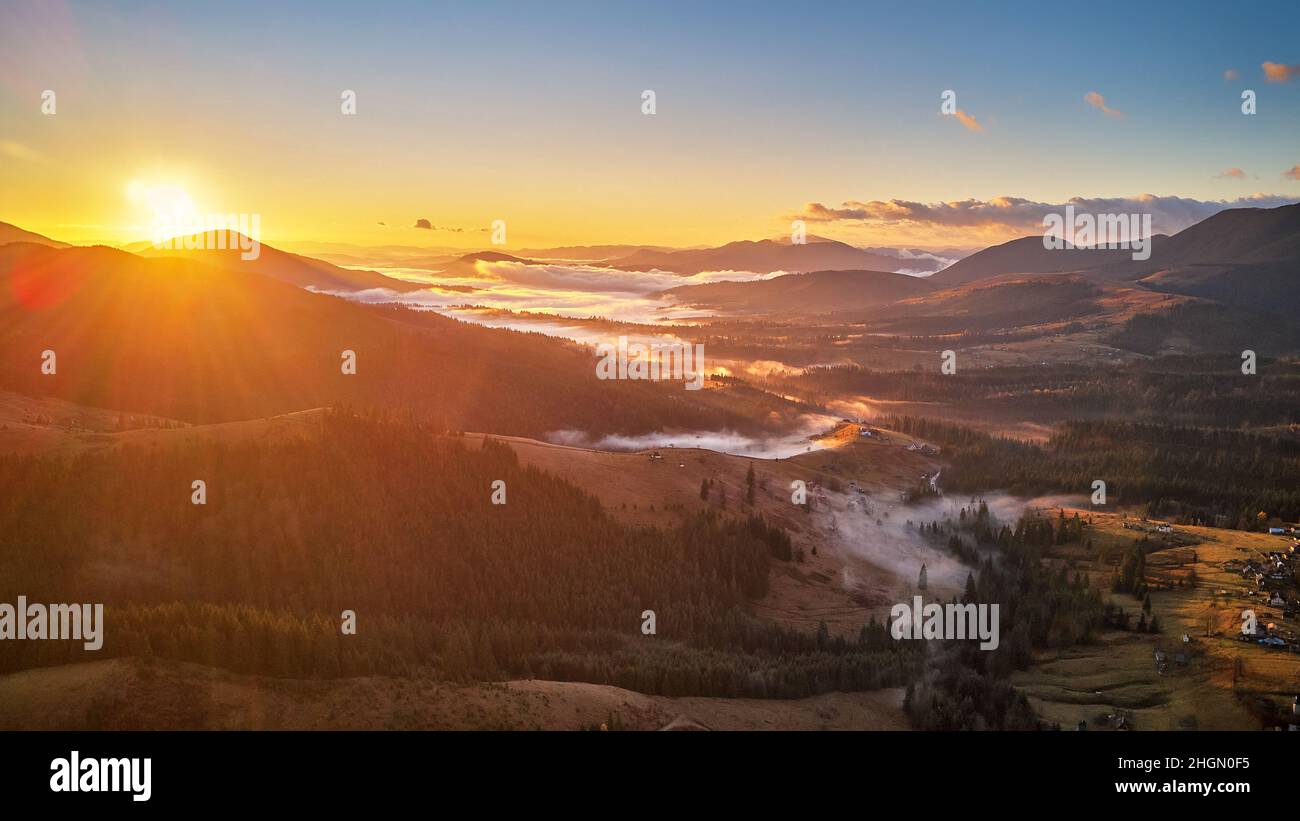 Colorful autumn sunrise over foggy woodland. Mountain forest covered by ...