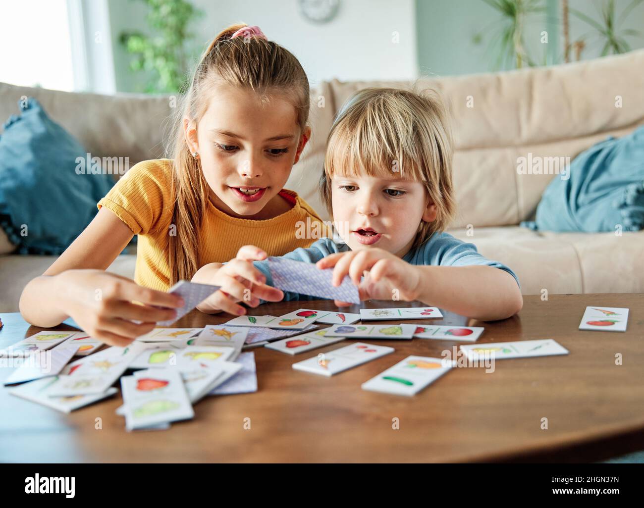 child girl boy childhood kid brother sister love family together fun happy joy happiness cute play playing board game card Stock Photo