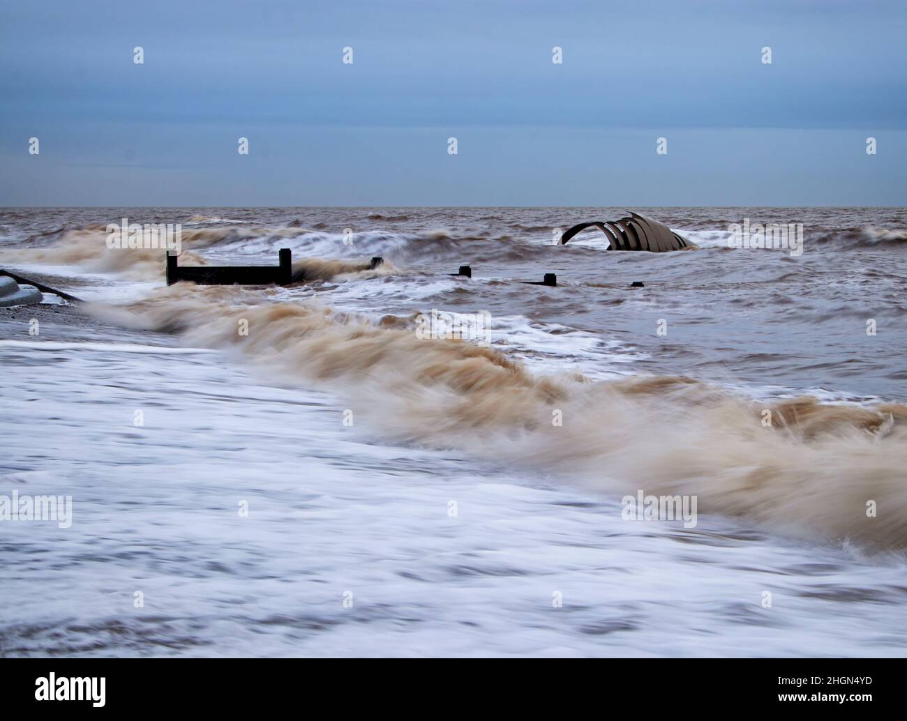 Looking along Cleveleys beach at high tide, with Mary's Golden Shell and groynes part covered in water Stock Photo