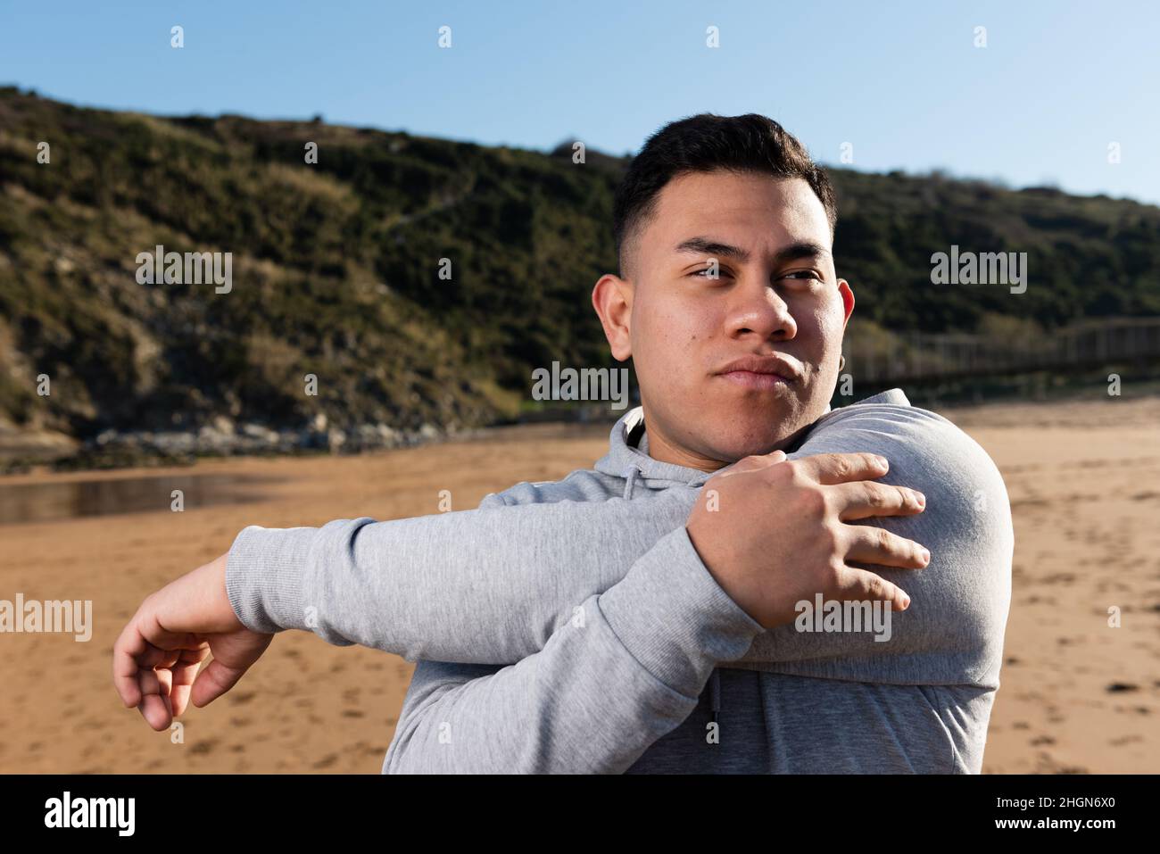Hispanic man stretching arms at the beach Stock Photo