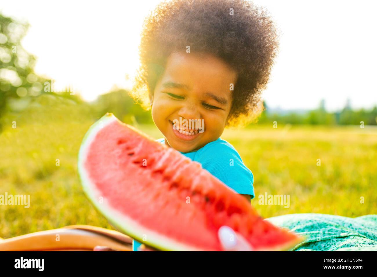 multicultural mexcan little curl with curls hair eating sweet red watermelon in park at picnic Stock Photo