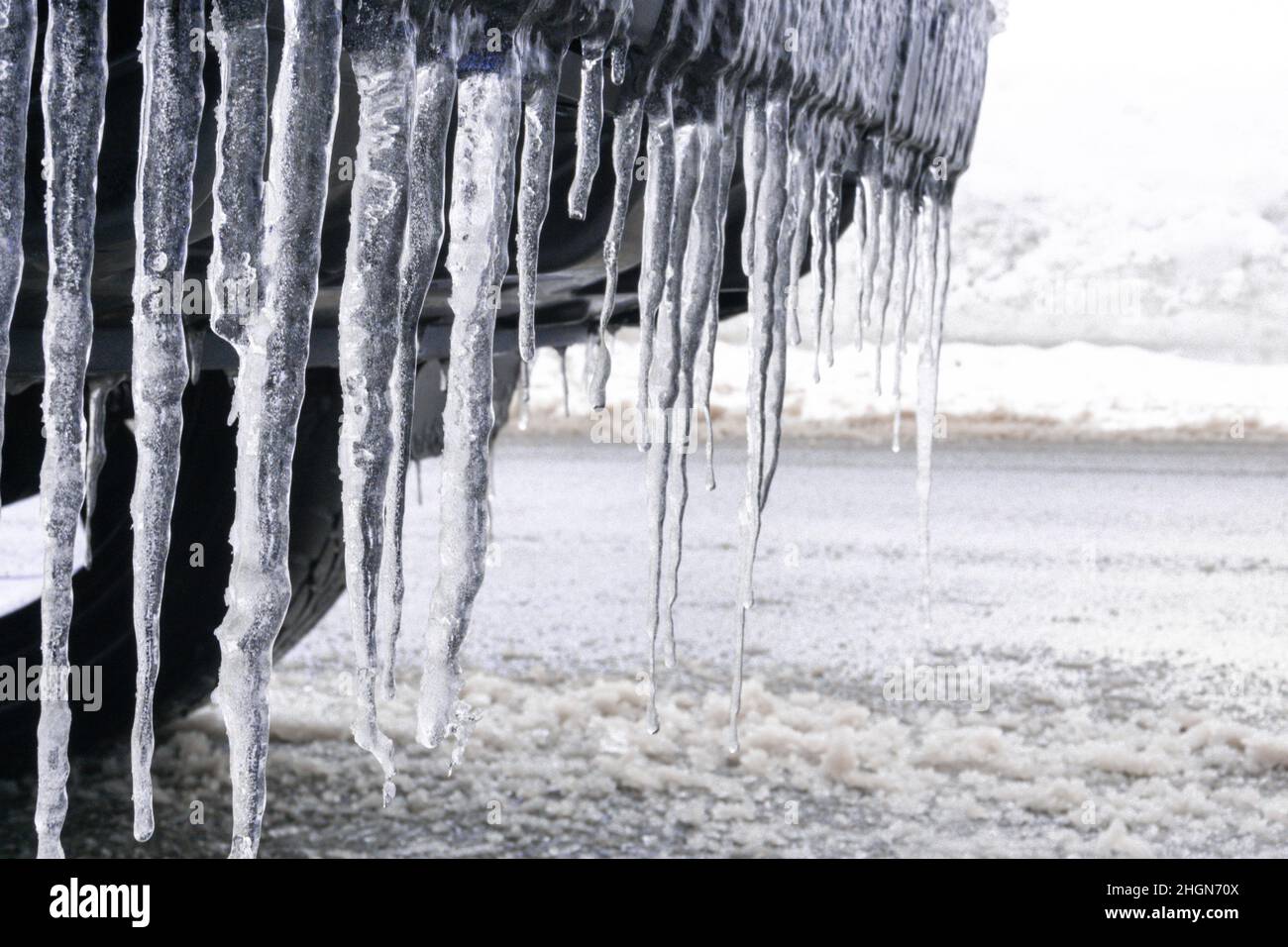 Long, cold and sharp icicles hang in the front of a car Stock Photo