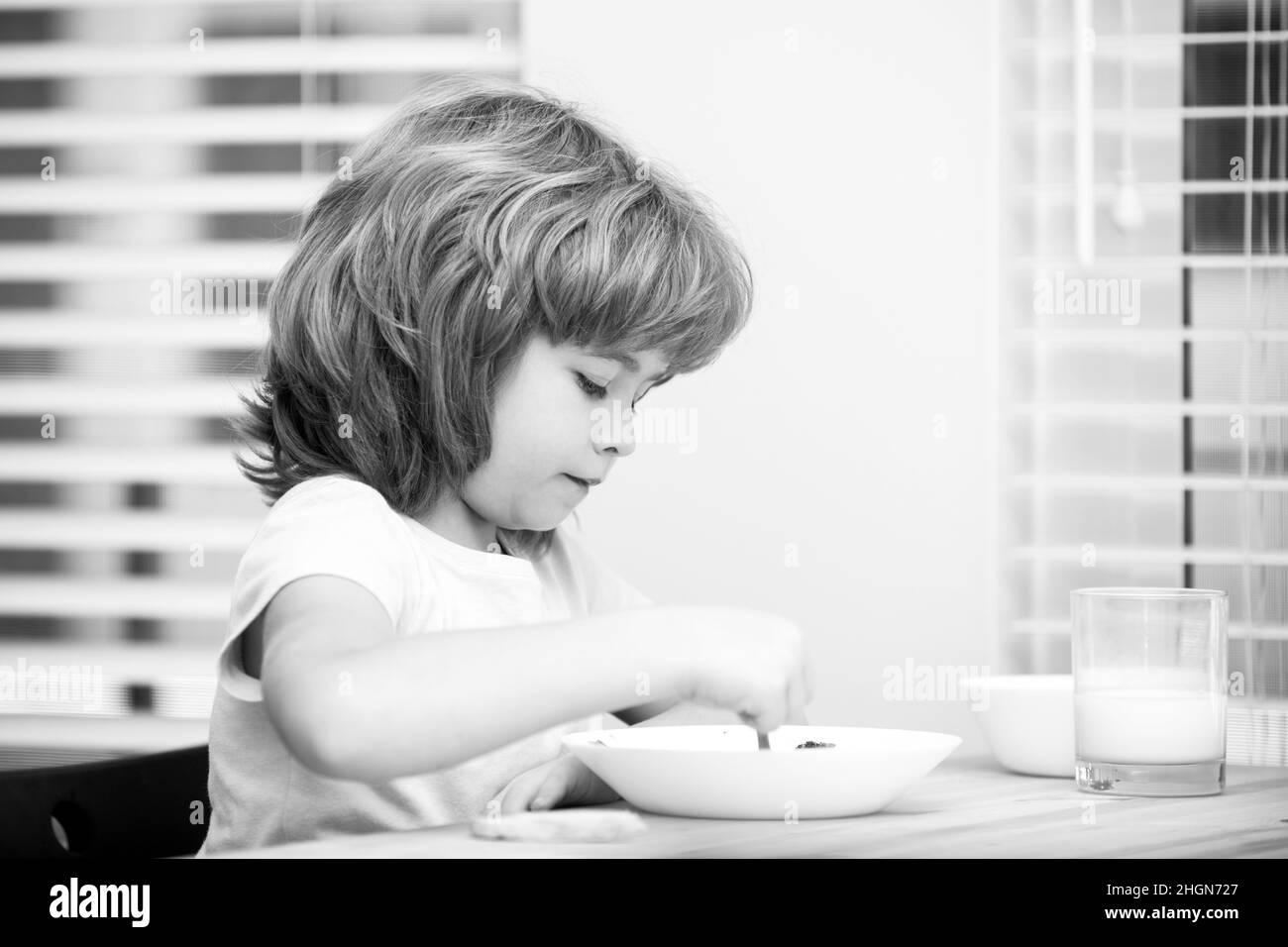 Caucasian toddler child boy eating healthy soup in the kitchen. Healthy nutrition for kids. Stock Photo