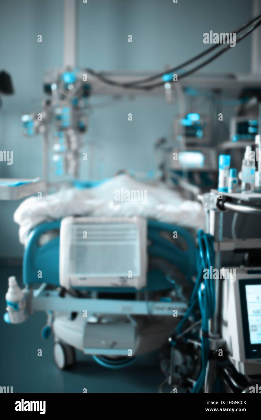 Blurred view of the modern equipped intensive care ward with comatose patient in the bed. Stock Photo