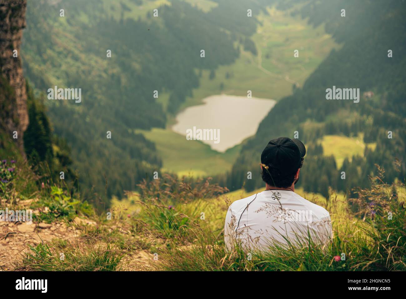 A man sits on the top of a mountain after a nice hike and admires the nature Stock Photo