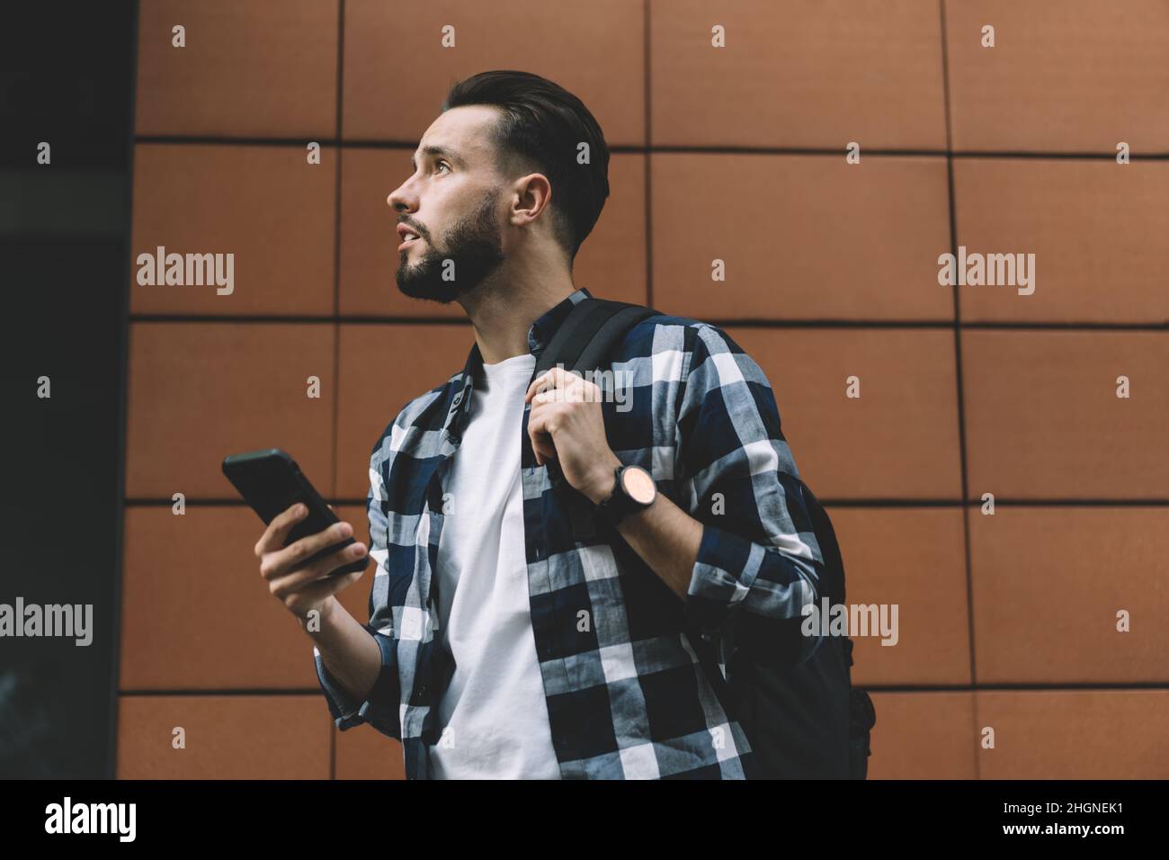 pensive male blogger with mobile gadget looking away Stock Photo