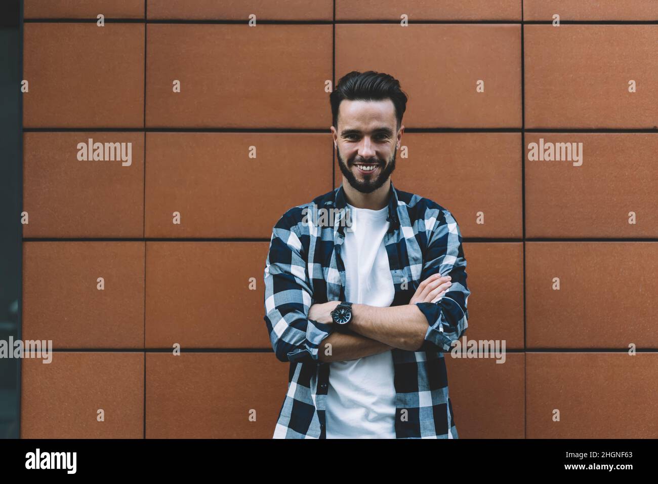 Half length portrait of cheerful male tourist with crossed hands smiling at camera during travel time Stock Photo