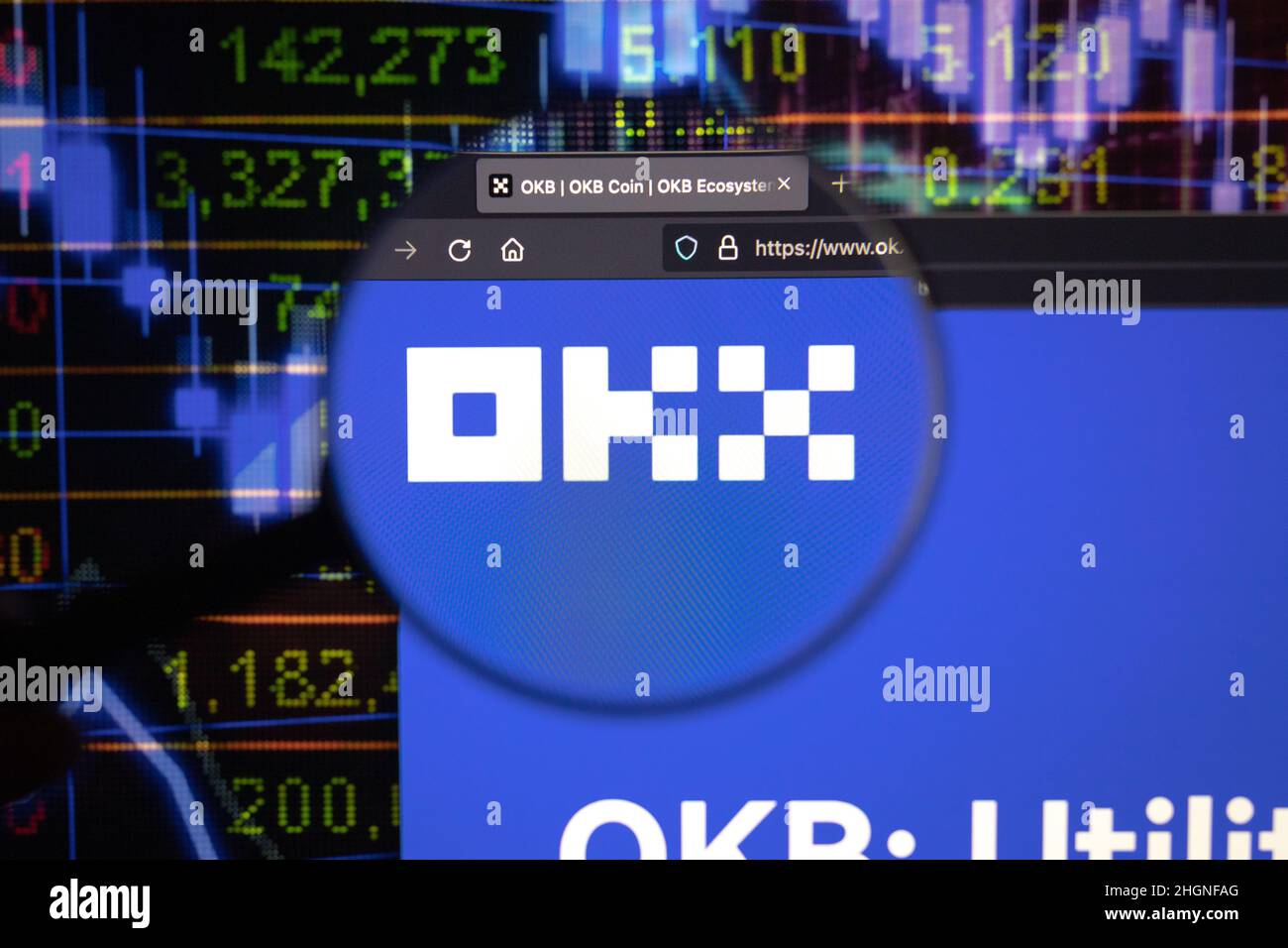 OKX crypto company logo on a website, seen on a computer screen through a magnifying glass. Stock Photo
