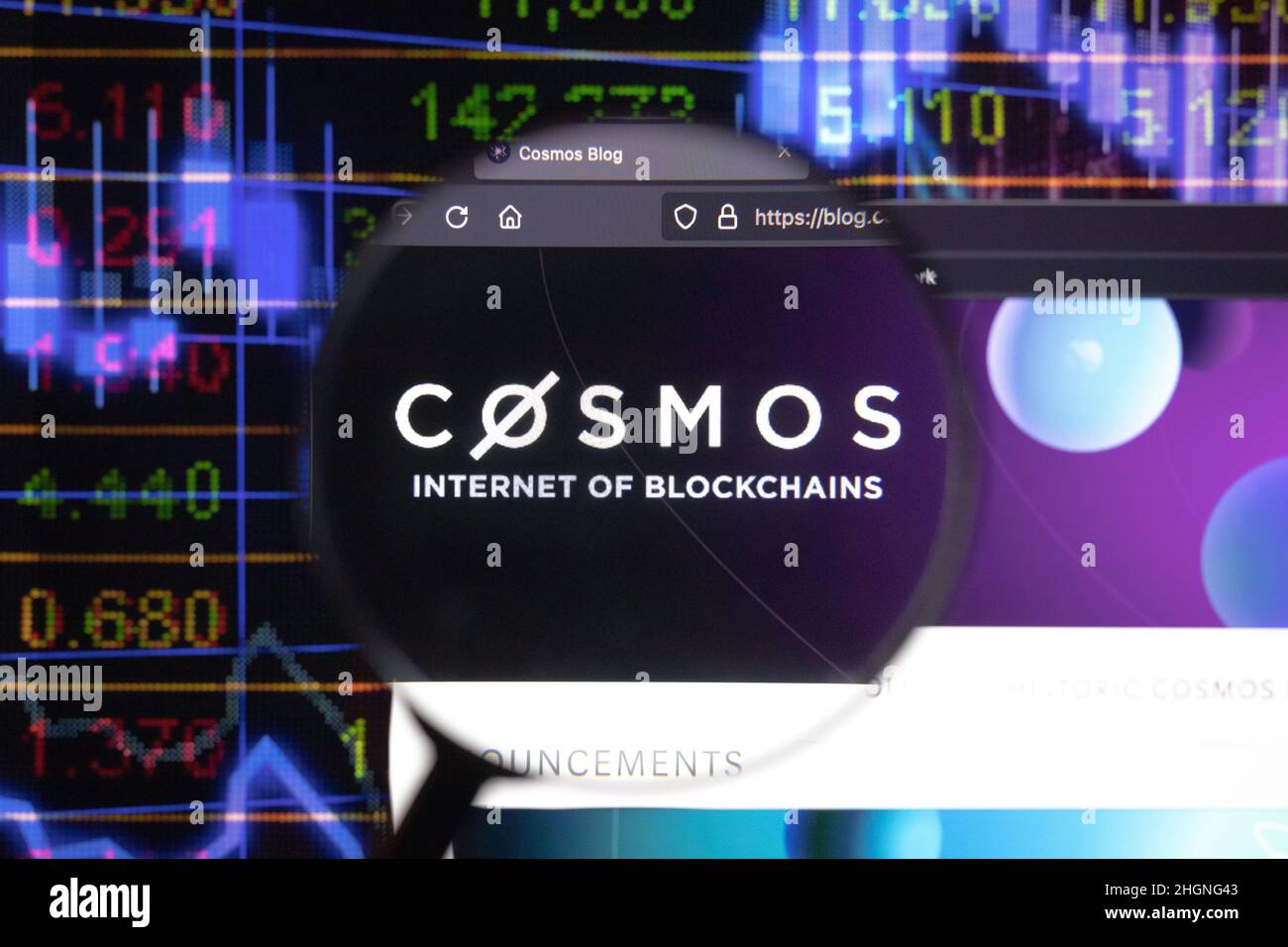 Cosmos crypto company logo on a website, seen on a computer screen through a magnifying glass. Stock Photo