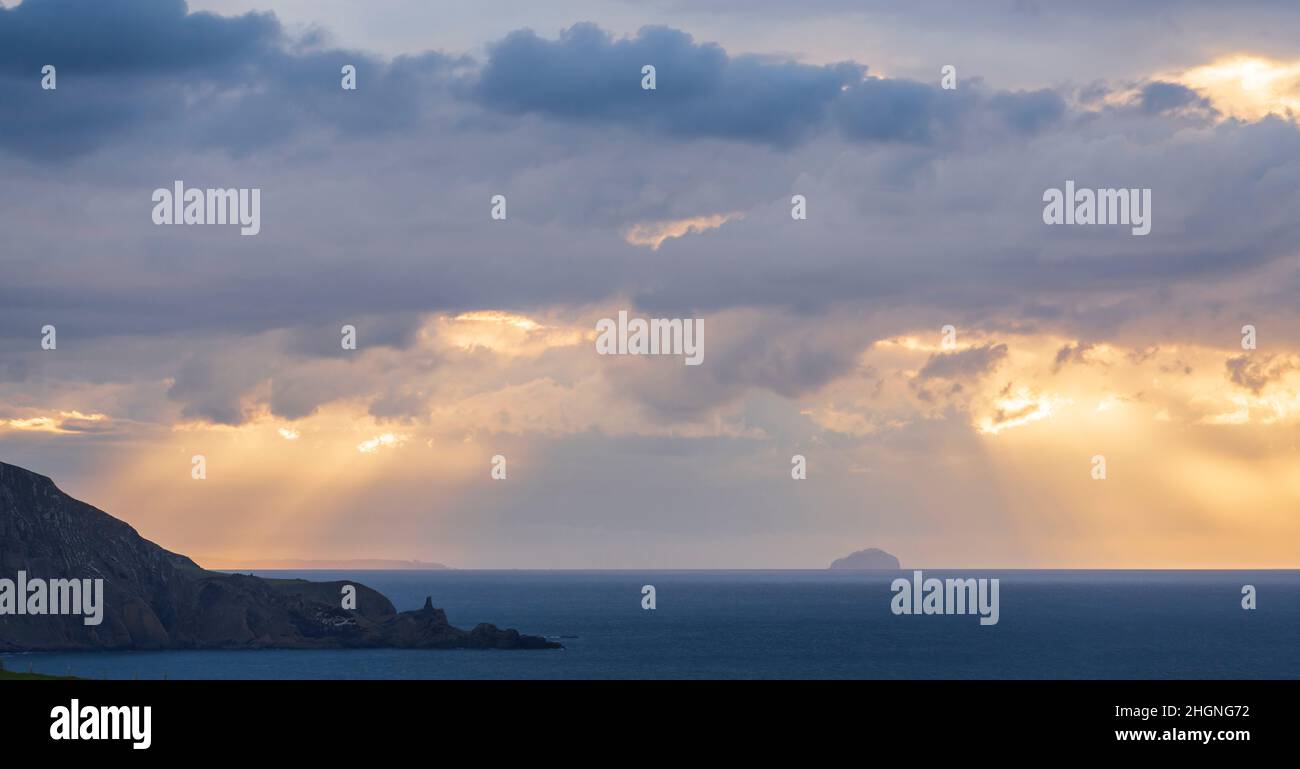 Late evening sun through clouds over the Bass Rock, seen from St Abbs Head, Scotland Stock Photo