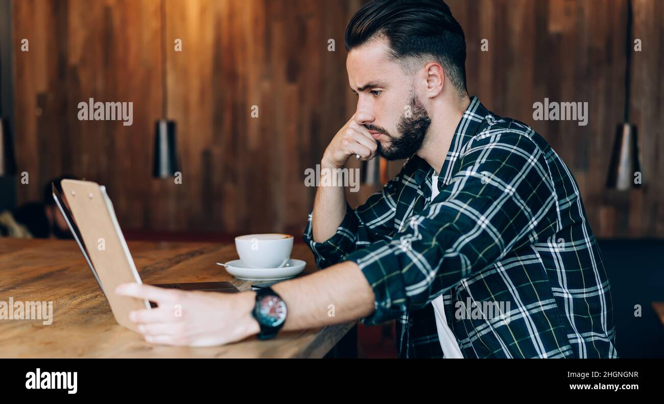 confused copywriter checking text notes during freelance remote working with laptop computer Stock Photo