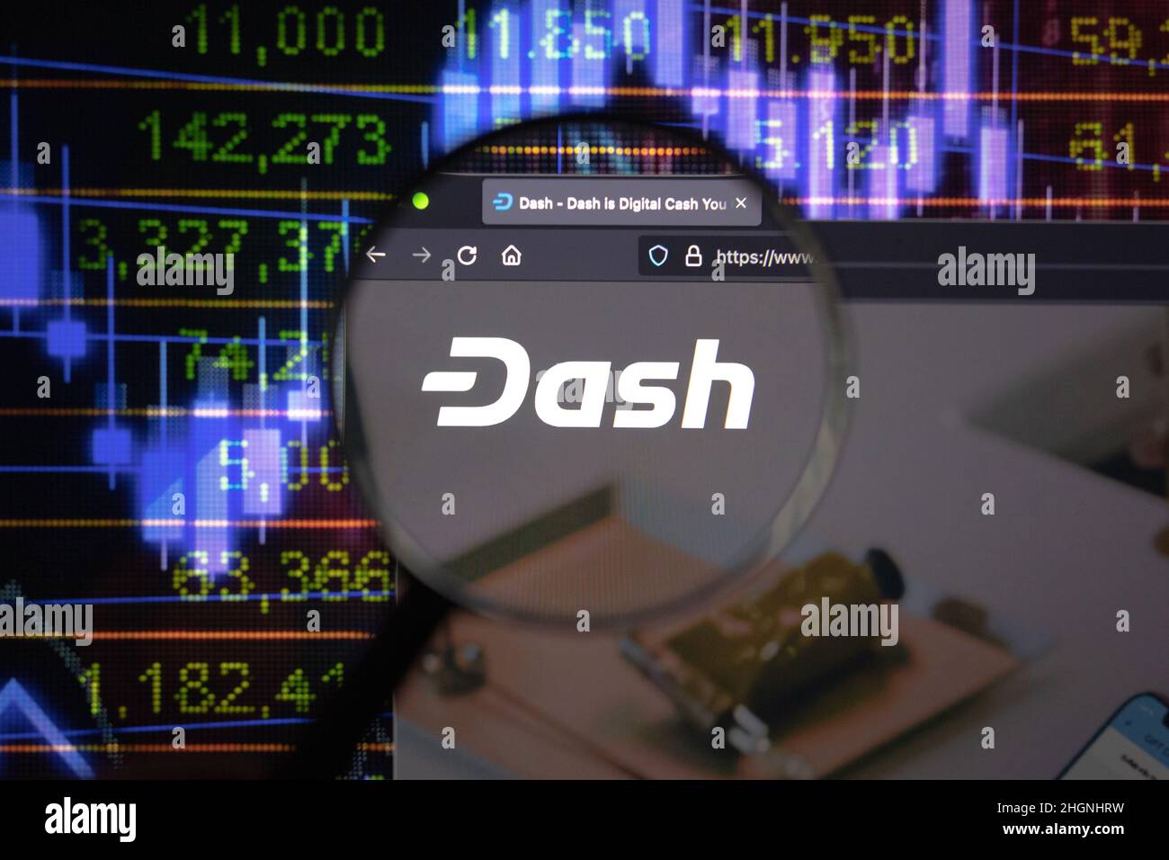 Dash crypto company logo on a website, seen on a computer screen through a magnifying glass. Stock Photo