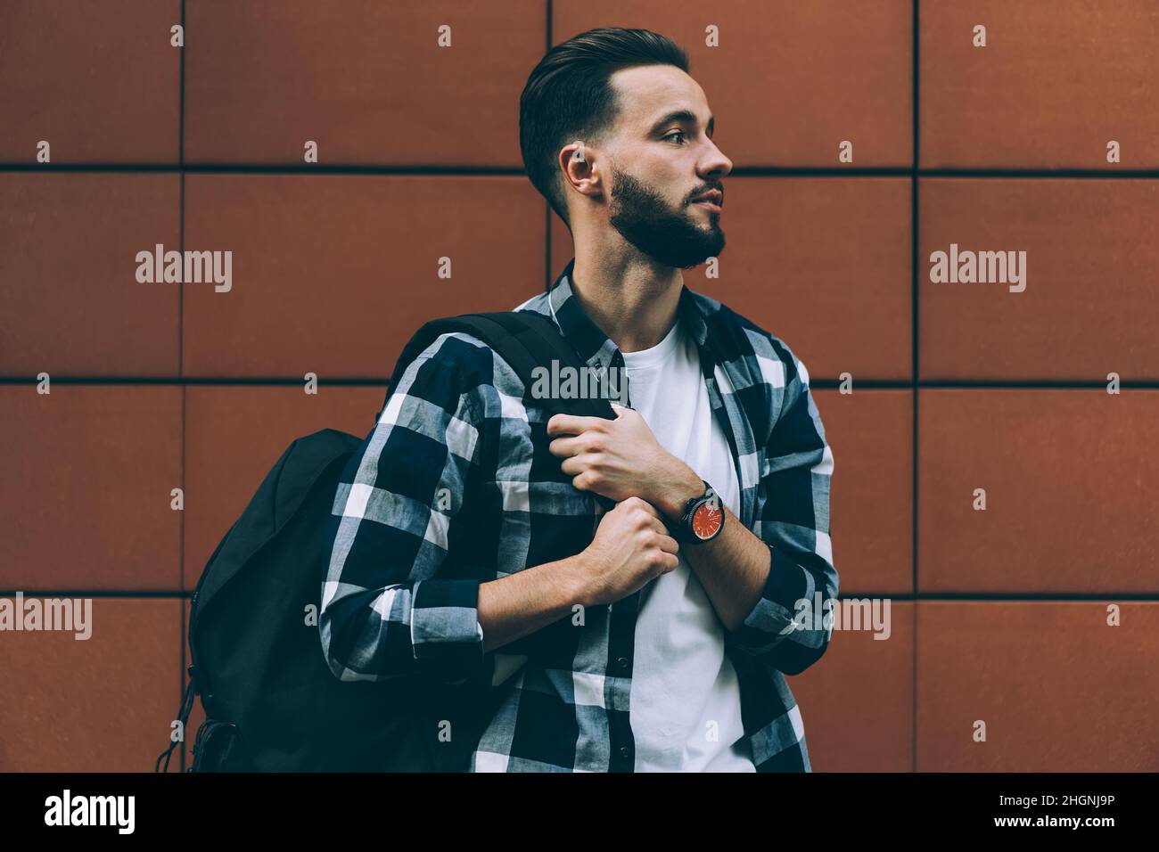 handsome hipster guy with travel backpack feeling pondering at street Stock Photo
