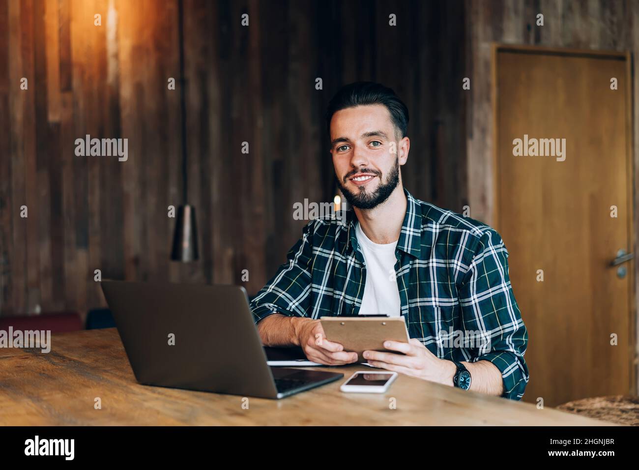 happy hipster guy working remotely in cafe interior sitting at desk with tech netbook Stock Photo