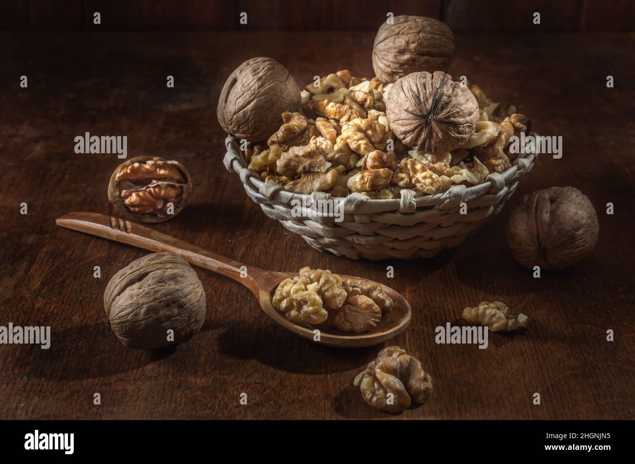 walnuts and kernels in a basket on a dark wooden background Stock Photo