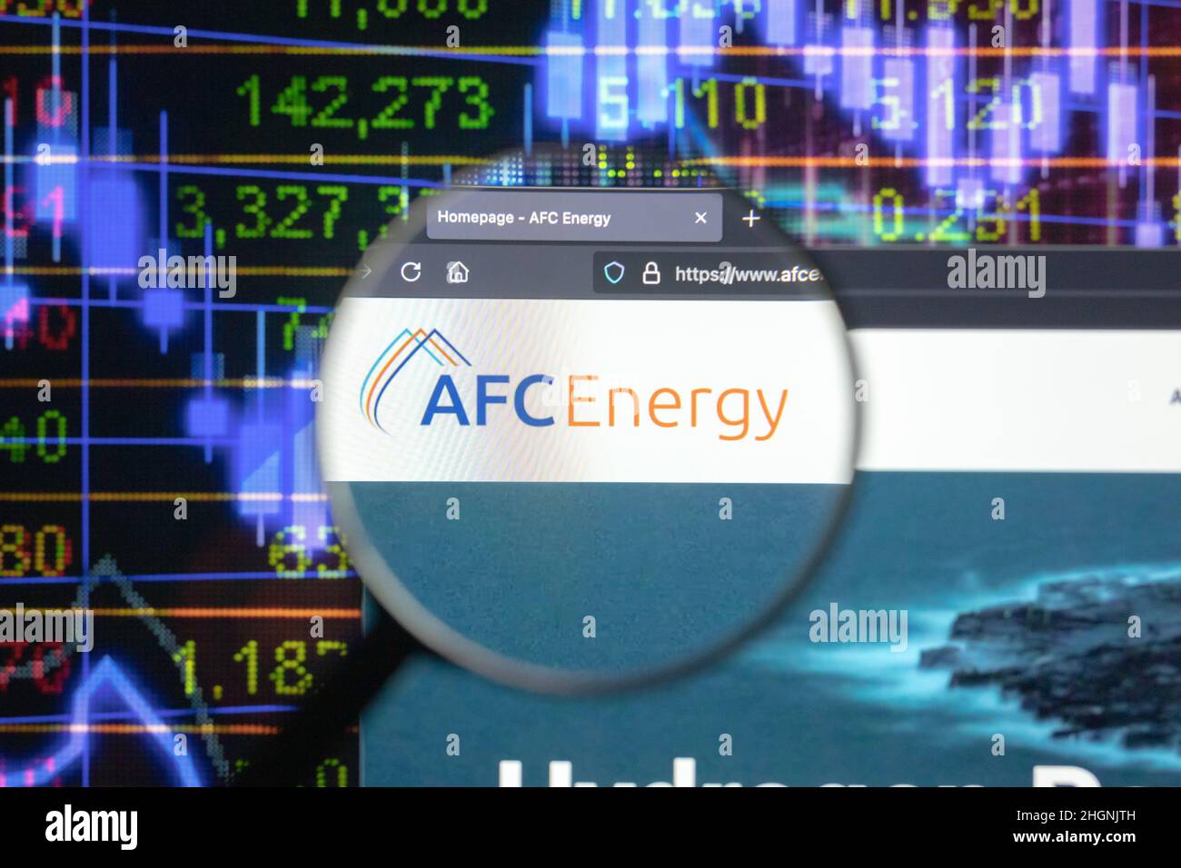 AFC Energy company logo on a website with blurry stock market developments in the background, seen on a computer screen through a magnifying glass. Stock Photo