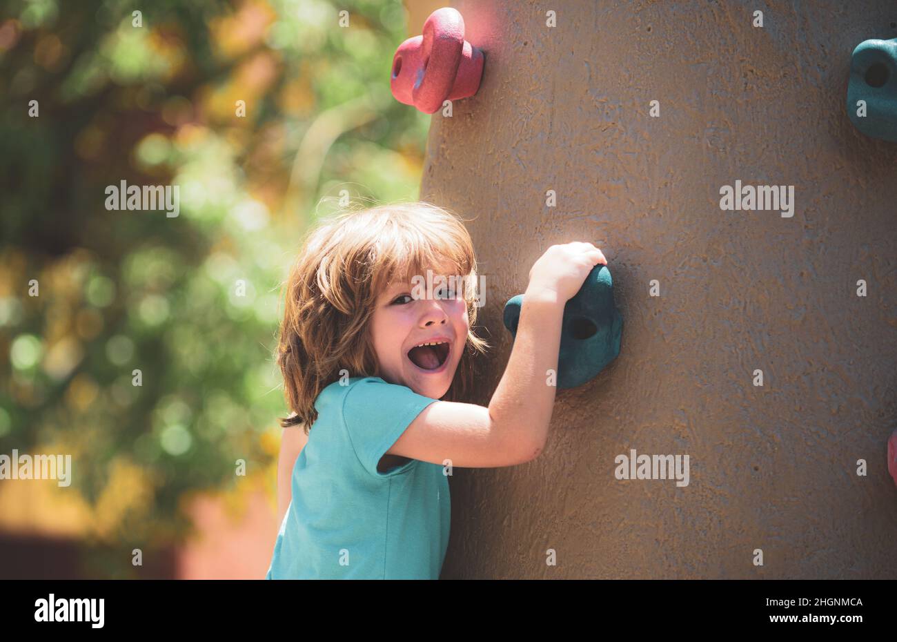 Insurance kids. Portrait of kid boy climbing on practical wall indoor, bouldering training. Health care insurance concept for family and children Stock Photo