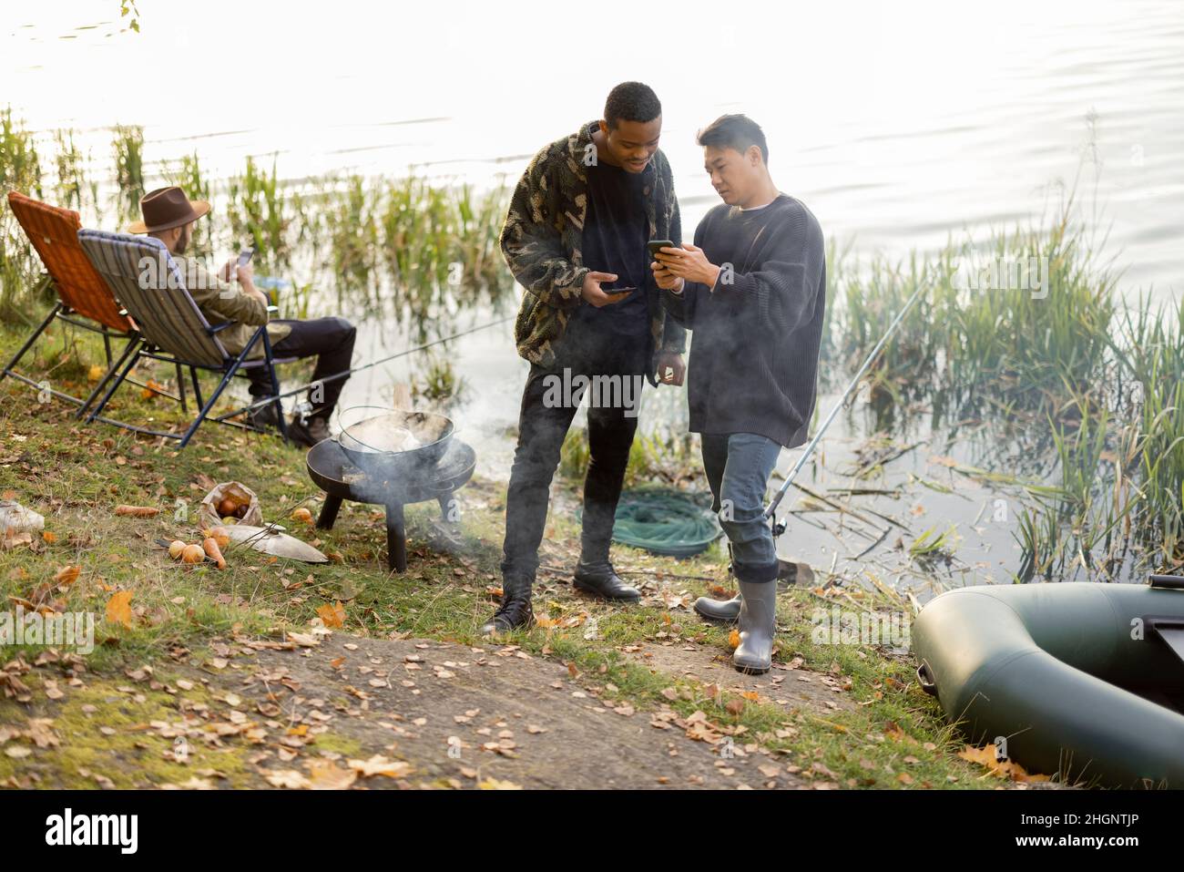 Men using smartphones during resting on pond coast Stock Photo