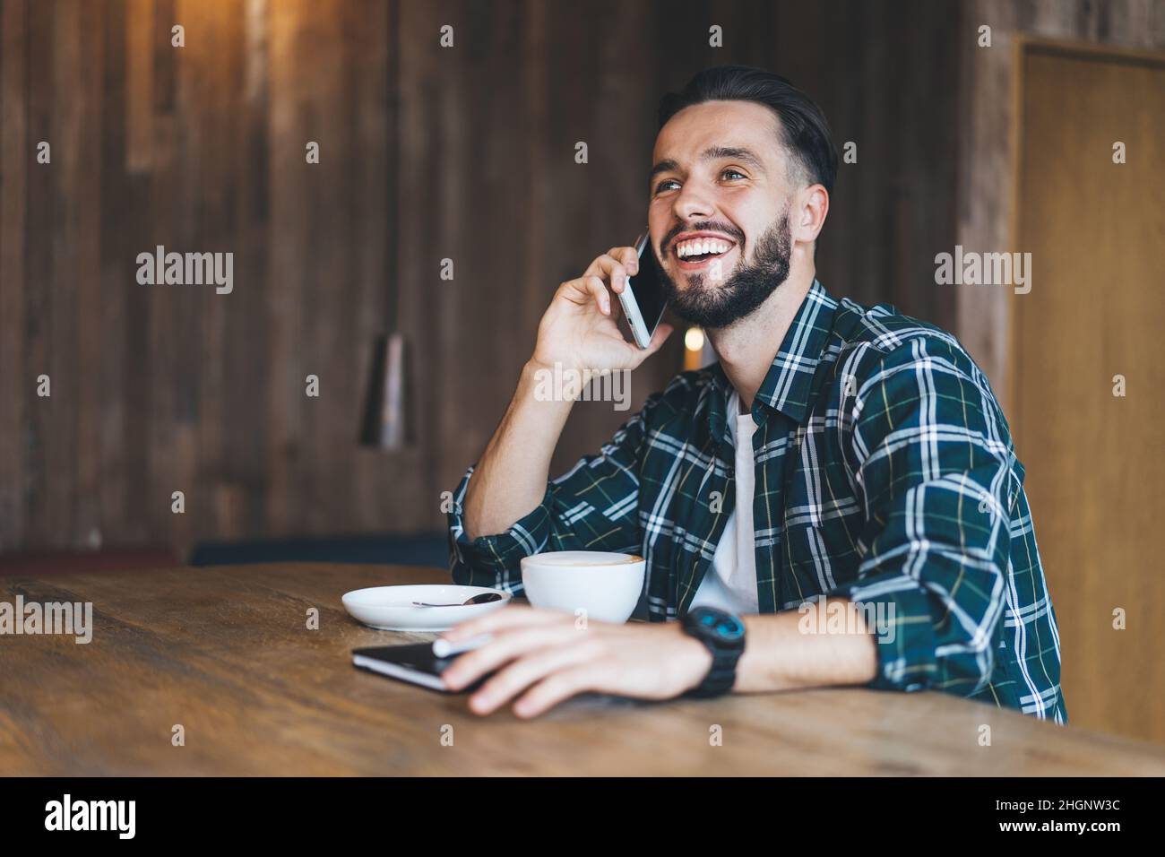 Cheerful Caucasian man using cellphone device for calling enjoying positive conversationv Stock Photo