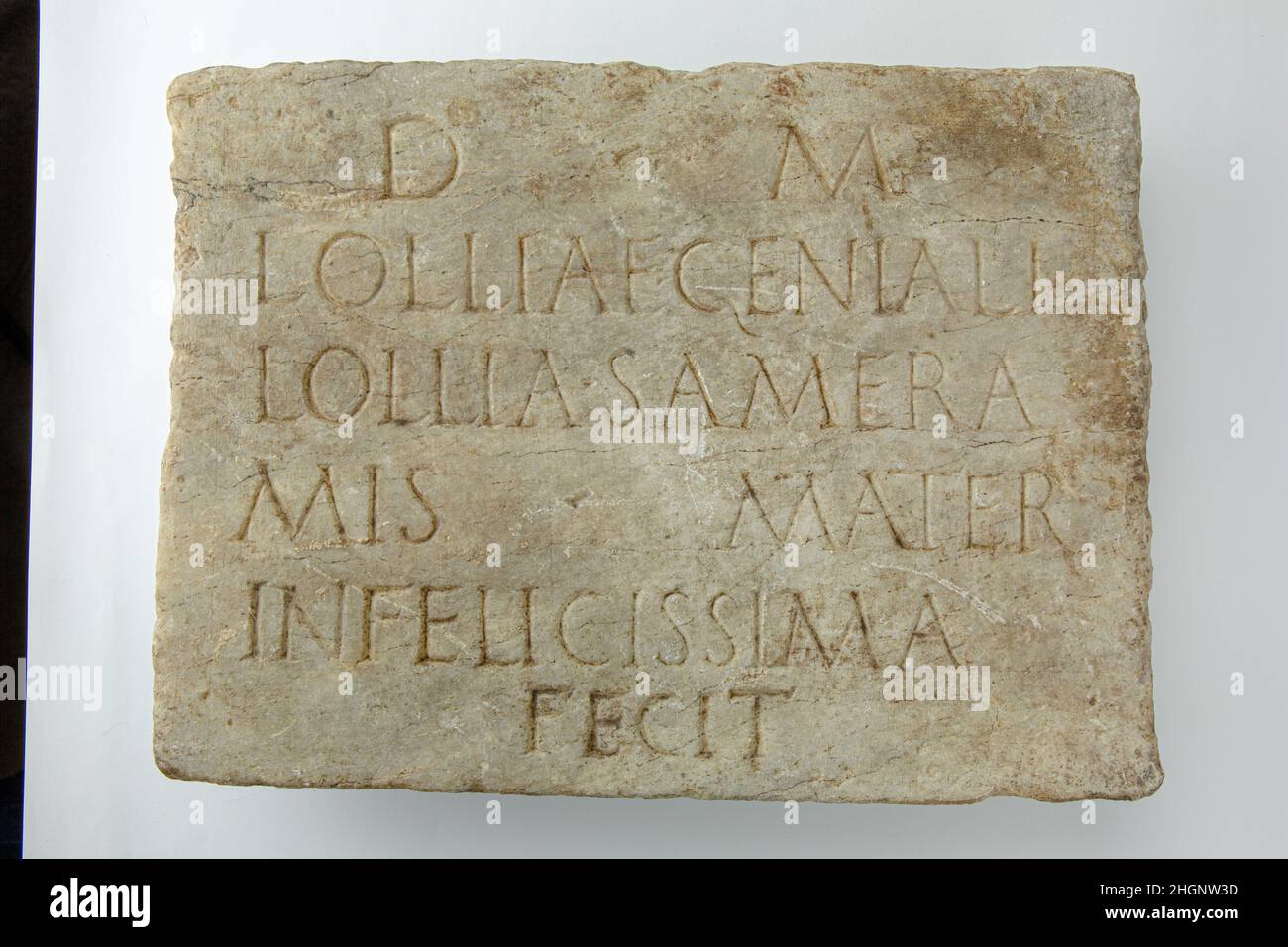 Marble plaque with funerary inscription 1st–2nd century A.D. Roman The inscription records the death of a woman called Lollia Genialis and says that the plaque was set up by her mother, Lollia Sameramis, who describes herself as infelicissima (most unfortunate). Such superlatives appear frequently in funerary inscriptions and provide insight into personal emotions such as the deep sense of loss felt by grieving parents.. Marble plaque with funerary inscription. Roman. 1st–2nd century A.D.. Marble. Imperial. Stone Sculpture Stock Photo