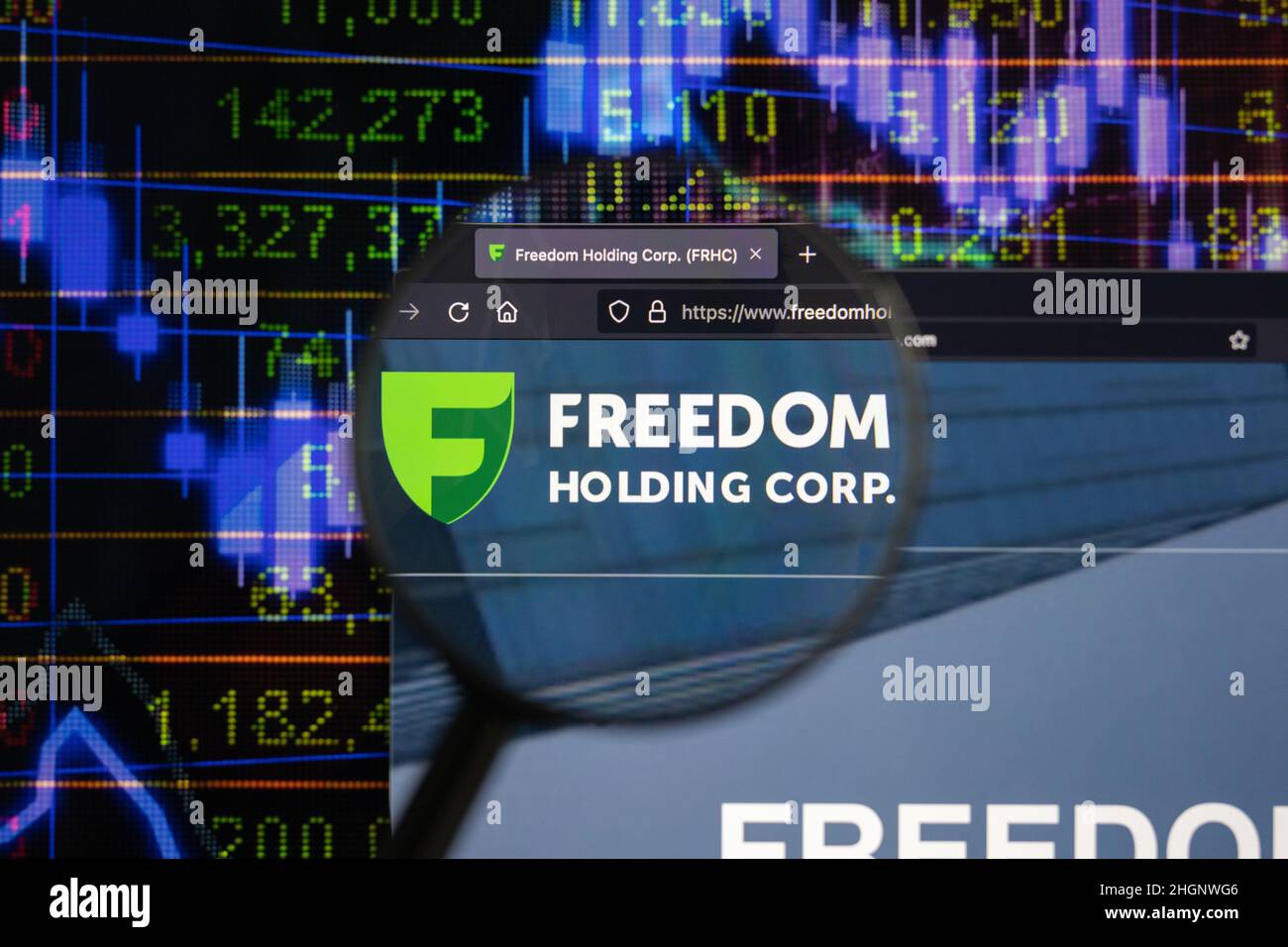 Freedom Holding Corp. company logo on a website with blurry stock market developments in the background, seen on a computer screen Stock Photo