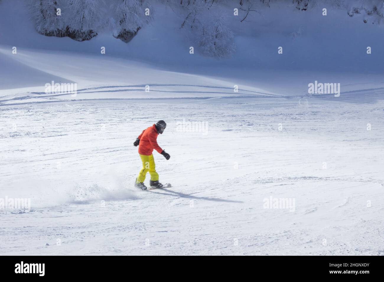 Man in warm clothes snowboarding downhill freestyle. Winter sports concept. Extreme sports in winter season. Snowboarder enjoying extreme sports in wi Stock Photo