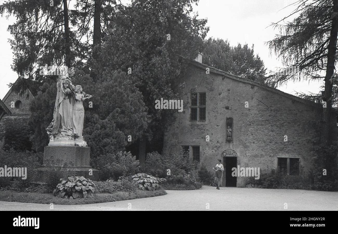 1950s, historical, exterior view from this era of La Maison Natale de Jeanne d'Arc, a two-storey stone farm building, with sloping roof, where Joan of Arc was born in the 15th century, Domremy-la-Pucelle, France. A statue stands in front of the house. Her birth house in Domrémy was preserved and became a museum. Also known as the 'The Maid of Orleans' this simple peasant girl is considered a national heroine in French culture, as believing that she was acting under the will of god, she led the French army to victory at Orleans in 1429 against the English during the Hundred Years War. Stock Photo