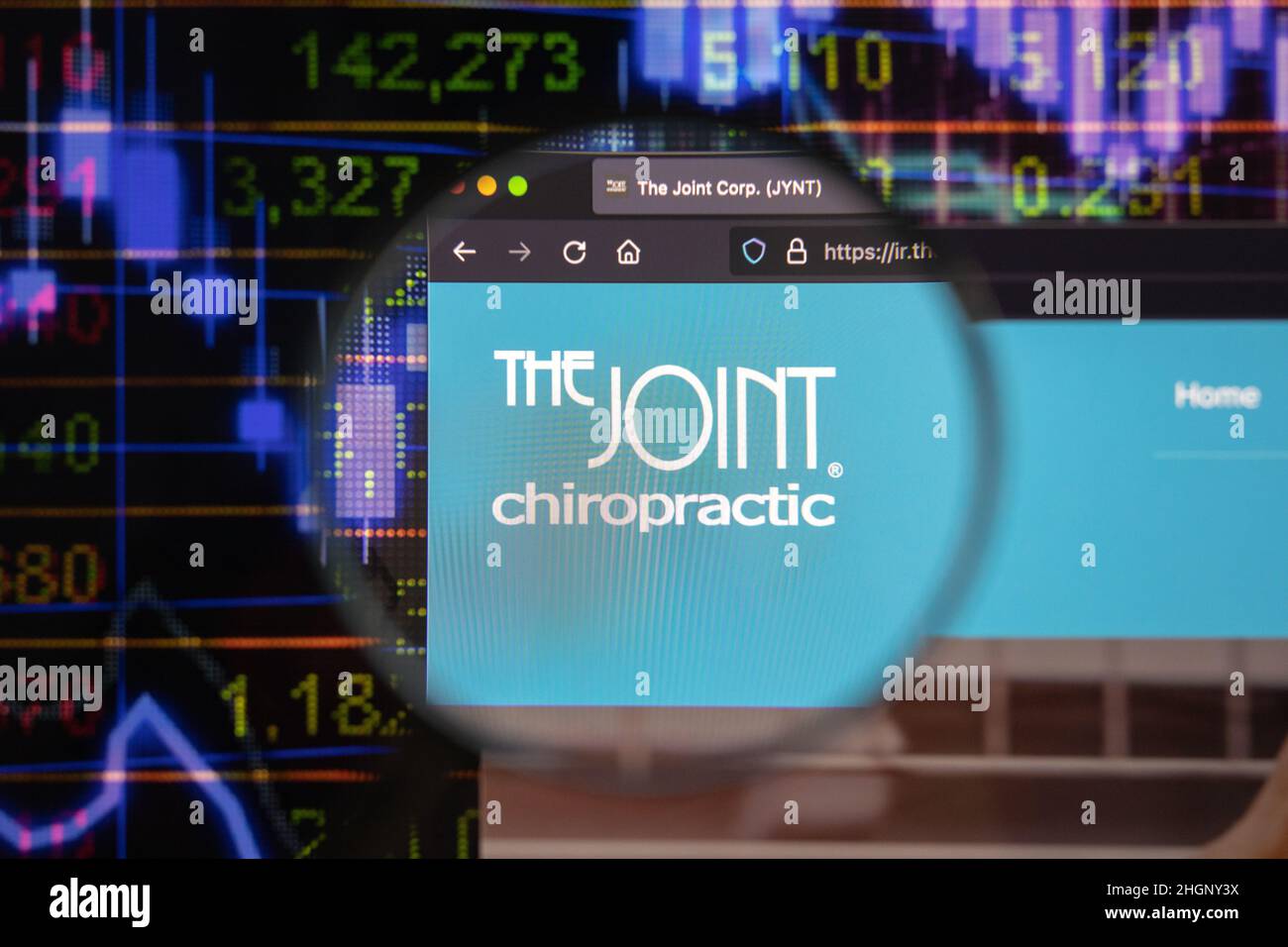 The Joint Chiropractic company logo on a website with blurry stock market developments in the background, seen on a computer screen Stock Photo