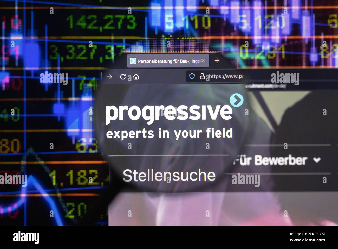 Progressive company logo on a website with blurry stock market developments in the background, seen on a computer screen through a magnifying glass. Stock Photo